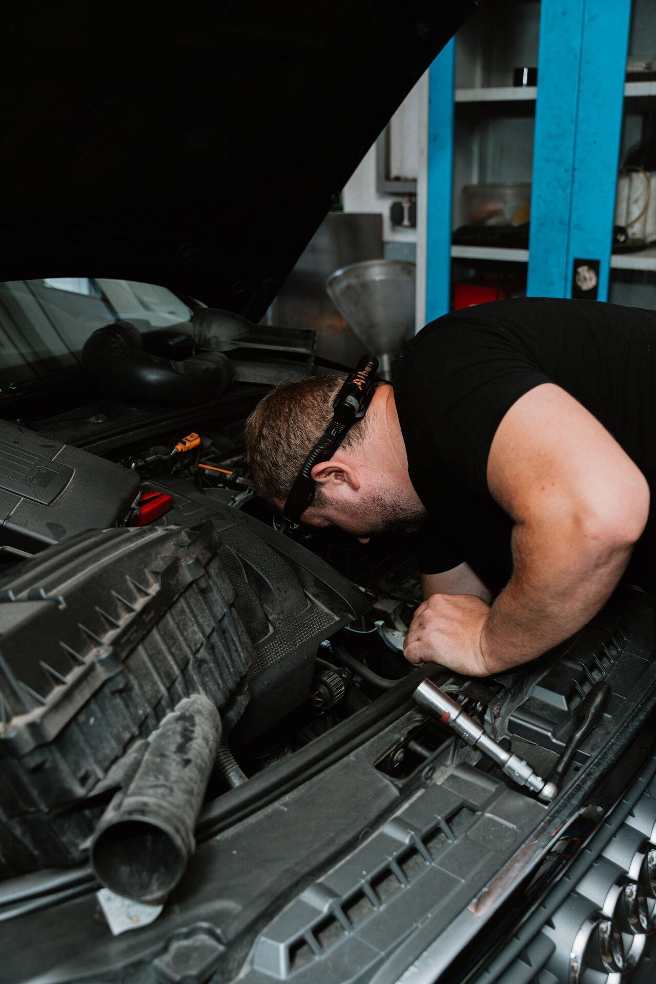 Mechaniker beugt sich über den Motorraum eines Fahrzeugs in der Werkstatt